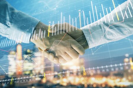 Double exposure of financial chart on cityscape background with two businessmen handshake. Concept of financial analysis and investment opportunitiesの写真素材