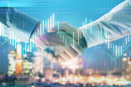 Double exposure of financial chart on cityscape background with two businessmen handshake. Concept of financial analysis and investment opportunitiesの写真素材