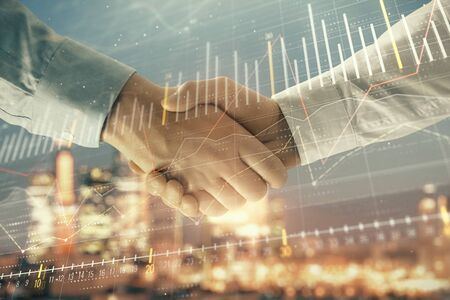 Double exposure of financial chart on cityscape background with two businessmen handshake. Concept of financial analysis and investment opportunitiesの写真素材