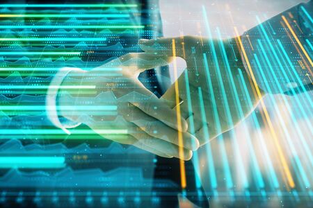 Double exposure of financial graph on cityscape background with two businessman handshake. Concept of stock market dealの写真素材