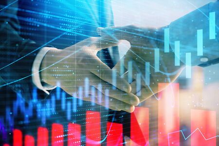 Double exposure of financial graph on cityscape background with two businessman handshake. Concept of stock market dealの写真素材