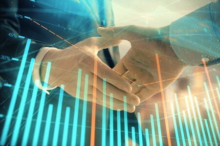 Double exposure of financial graph on cityscape background with two businessman handshake. Concept of stock market dealの写真素材