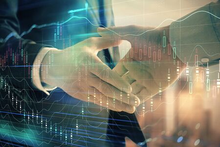 Double exposure of financial graph on cityscape background with two businessman handshake. Concept of stock market dealの写真素材