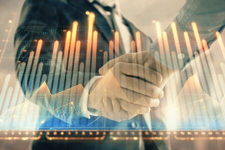 Double exposure of financial graph on cityscape background with two businessman handshake. Concept of stock market dealの写真素材
