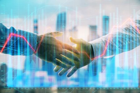 Double exposure of financial graph on cityscape background with two businessman handshake. Concept of stock market dealの写真素材