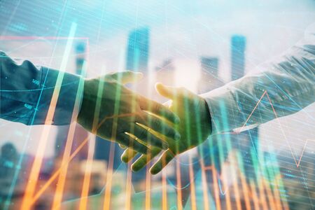Double exposure of financial graph on cityscape background with two businessman handshake. Concept of stock market dealの写真素材