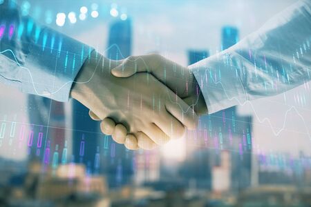 Double exposure of financial graph on cityscape background with two businessman handshake. Concept of stock market dealの写真素材