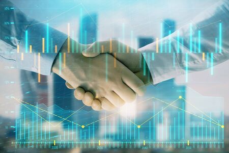 Double exposure of financial graph on cityscape background with two businessman handshake. Concept of stock market dealの写真素材