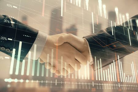 Double exposure of financial graph on cityscape background with two businessman handshake. Concept of stock market dealの写真素材