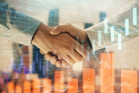 Double exposure of financial graph on cityscape background with two businessman handshake. Concept of stock market dealの写真素材