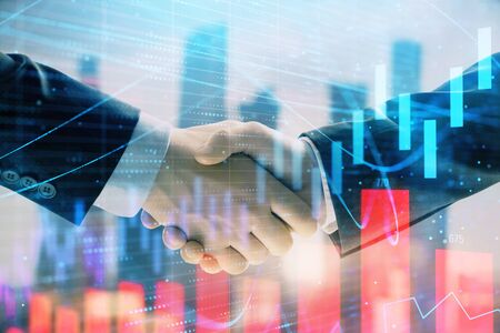 Double exposure of financial graph on cityscape background with two businessman handshake. Concept of stock market dealの写真素材