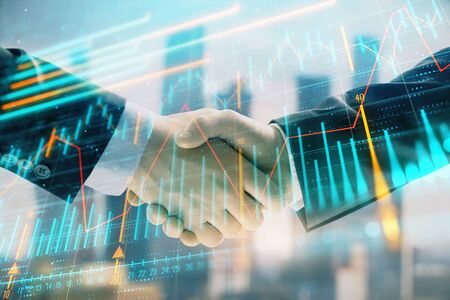 Double exposure of financial graph on cityscape background with two businessman handshake. Concept of stock market dealの写真素材