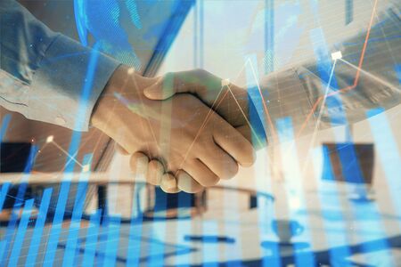 Multi exposure of financial chart and map on office background with two businessmen handshake. Concept of success in businessの写真素材