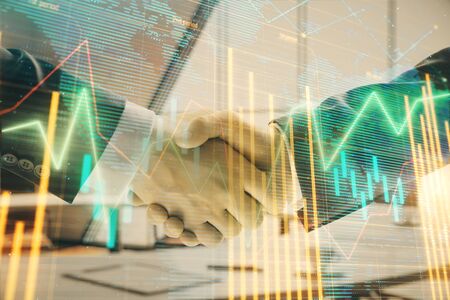 Multi exposure of financial chart and map on office background with two businessmen handshake. Concept of success in businessの写真素材