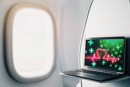 Laptop closeup inside airplane with heart health pic on screen. Medical education concept. 3d rendering.の写真素材