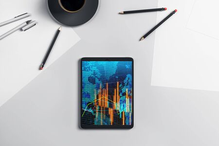 Digital tablet closeup top view with financial graph and partial world map on screen. Online international trading application concept. 3d rendering.の写真素材