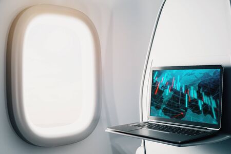 Laptop closeup inside airplane with forex graph and world map on screen. Financial market trading concept. 3d rendering.の写真素材