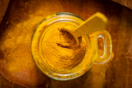 ground turmeric in a glass jar on wooden background