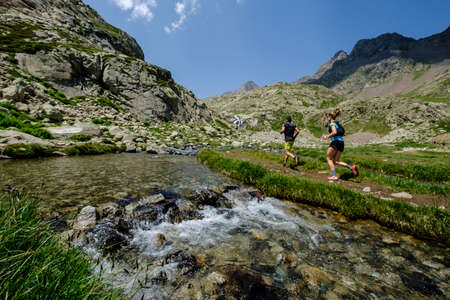 couple of mountain runners next to a river, Ibones azul and BachimaÃ±a alto route, Huesca province, Spainのeditorial素材