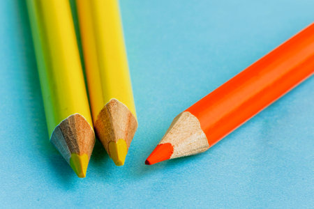 Yellow pencils and orange pencil on blue backgroundの写真素材