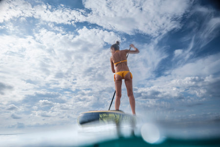 woman paddling on a surfboard under a dramatic sky, Estalella, coast of Llucmajor, Majorca, Balearic Islands, Spainの写真素材