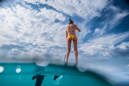 woman paddling on a surfboard under a dramatic sky, Estalella, coast of Llucmajor, Majorca, Balearic...