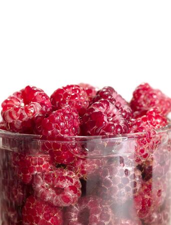 Red tasty raspberry in the glass mug on white background. Is not isolated image.