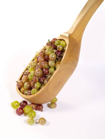 Ripe gooseberries in the wooden spoon, on bright background. Is not isolated imageの写真素材