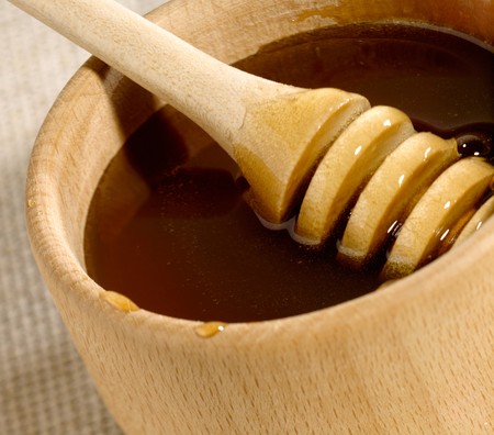 Honey in the wooden bowl with spoonの写真素材