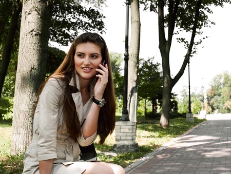 young beauty woman calling to someone on the the park benchの写真素材