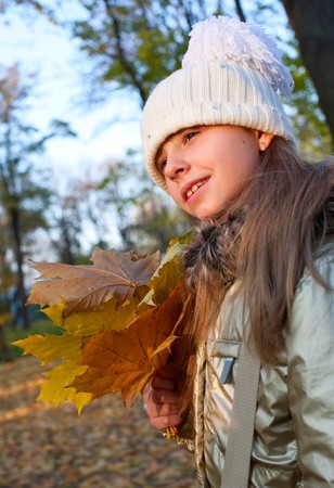 young girl with golden fallen mapple leaves in her handsの写真素材