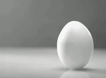 Simple as    White egg over desk with reflection and shadowの写真素材