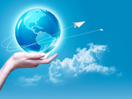 Female arm holding Earth  globe against blue skies, environmental backgrounds
