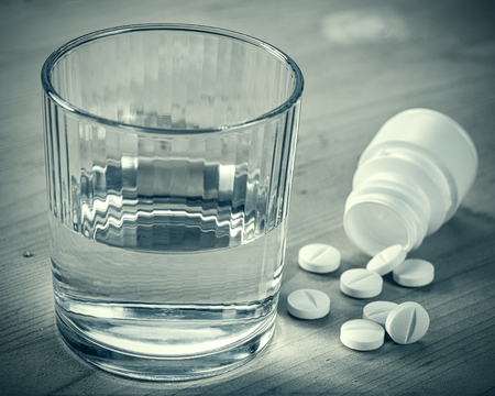 Depression. Abstract medical backgrounds with pills and glass of water over wooden deskの写真素材