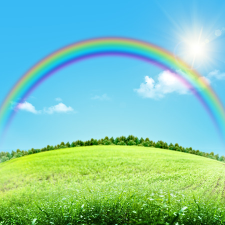 Dreamy natural landscape with green hills under blue skies and funny rainbowの写真素材