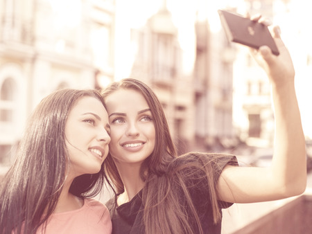 Couple of young adult girls making a selfie with smartphoneの写真素材