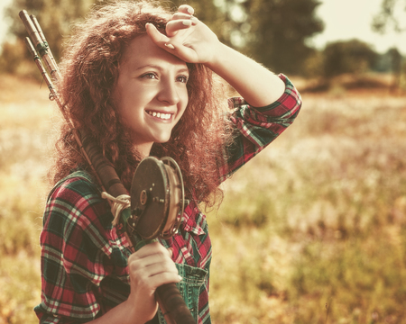 Fisher woman. Retro styled female portrait with wintage fishing pole, walking to the summer riverの写真素材