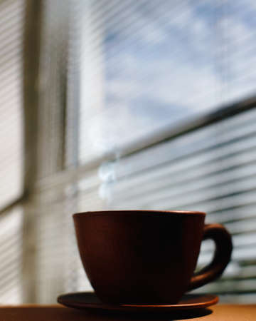 Morning coffee. Cup and plate close to window, under the sunlightの写真素材