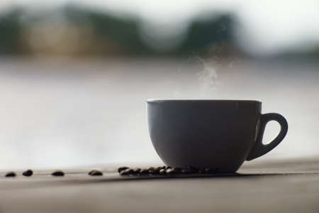 Morning on the river bank. A cup of delicious aromatic coffee on the table