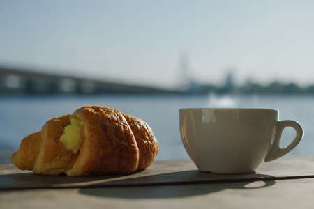 Morning on the river bank. A cup of delicious aromatic coffee on the tableの写真素材