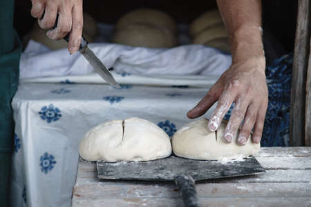 The baker prepares the dough for baking bread in a rural oven. Ukrainian villageの写真素材