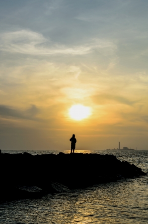 Sunset with lonely woman in Thai beachの写真素材