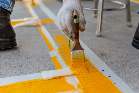 The man is painting the the yellow line on the concrete roadの写真素材