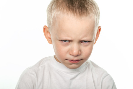 Boy with frowning face looking at camera on white background