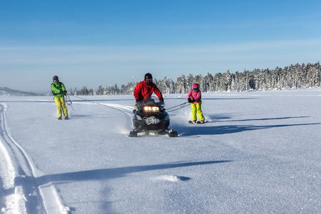 Skiers go after snowmobile using ropeの写真素材