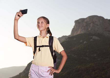Young woman hiker taking selfie with smart phone at mountainsの写真素材