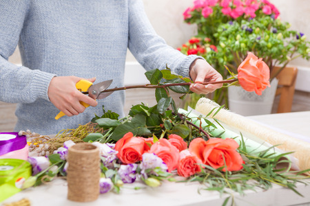 Florist at work. Female hands pruning rose in flowers shop.の写真素材