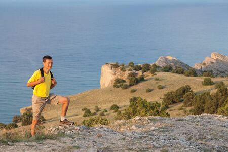 Hiker with backpack standing on a rock  over sea