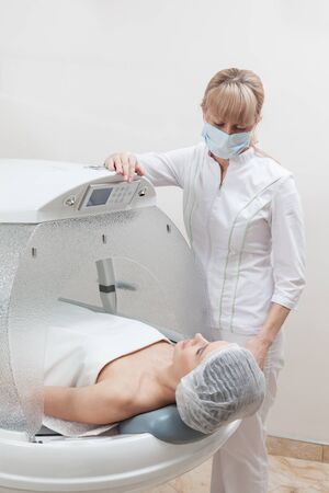 Woman lying in the capsule at the spa salon