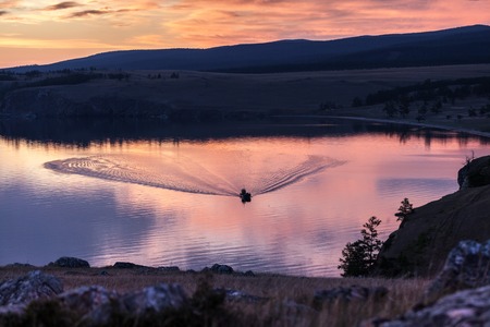 Dramatic red sunset over baikal lake with a sailboat and a redskyの写真素材